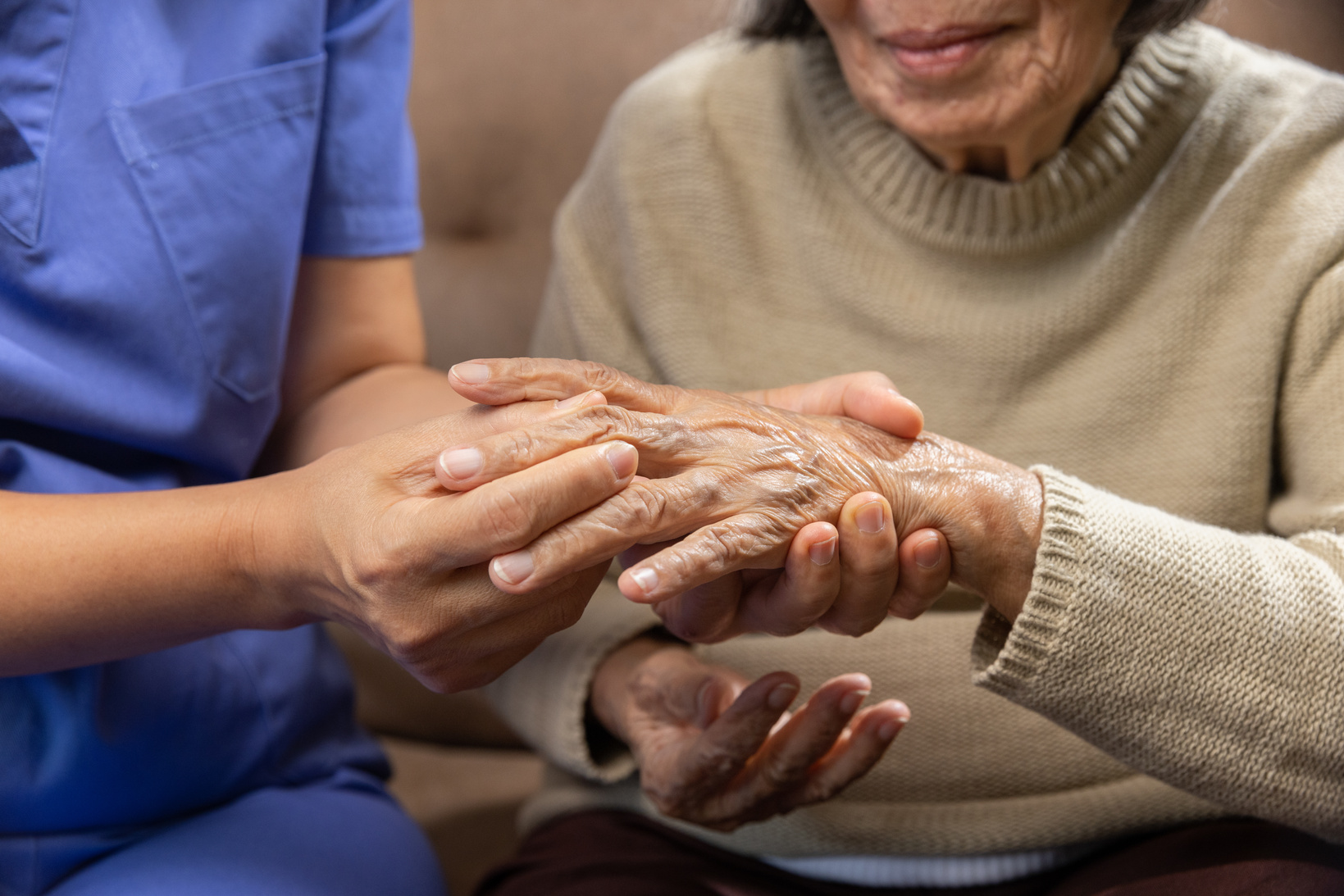 Caregiver massaging wrist of elderly woman in painful swollen go